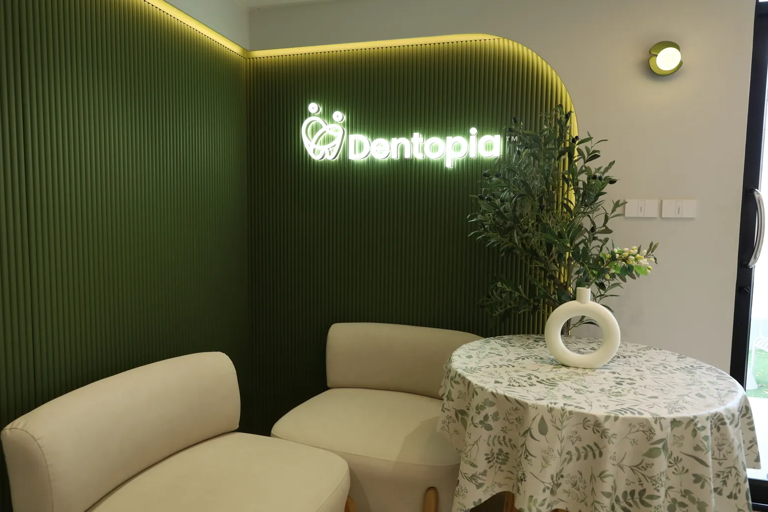 มุมคาเฟ่ผนังสีเขียวพร้อมป้ายไฟโลโก้ Dentopia