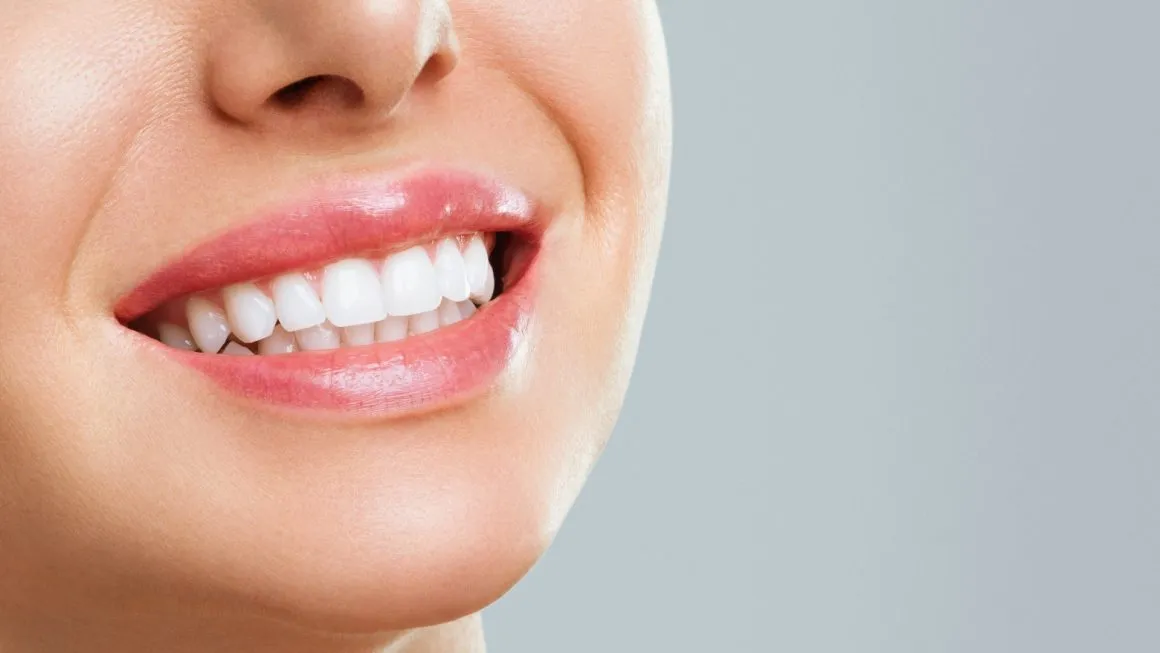 A close-up of a smile with even, light-coloured teeth.