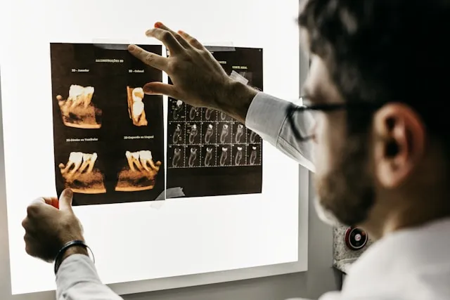 A dentist examining 3D dental scans on a lightbox.